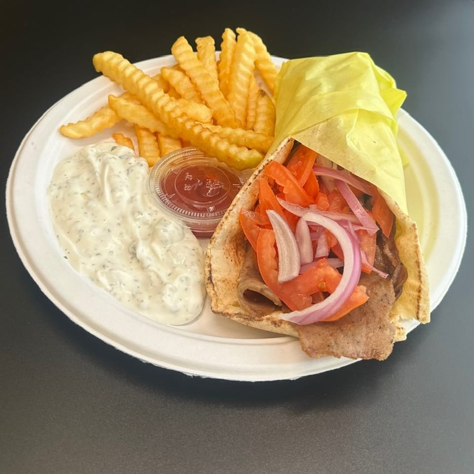 Mediterranean gyro with meat, tomatoes, and onions, served with crinkle-cut fries, tzatziki, and ketchup.