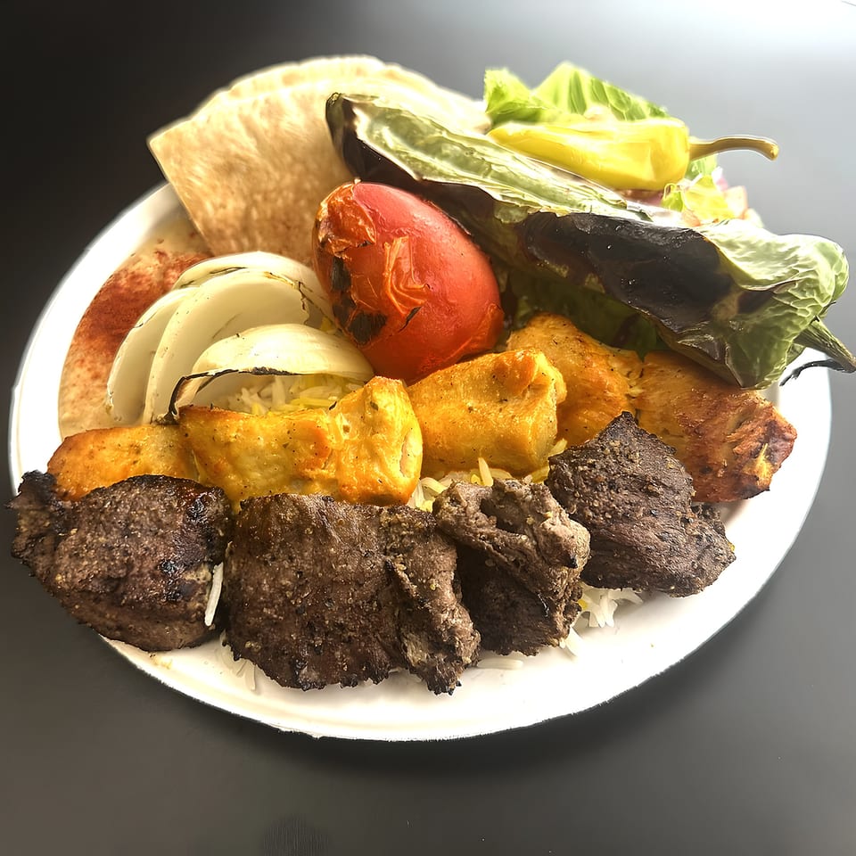 Grill Kabob's Mediterranean platter with grilled meats, vegetables, and pita bread on a white plate.